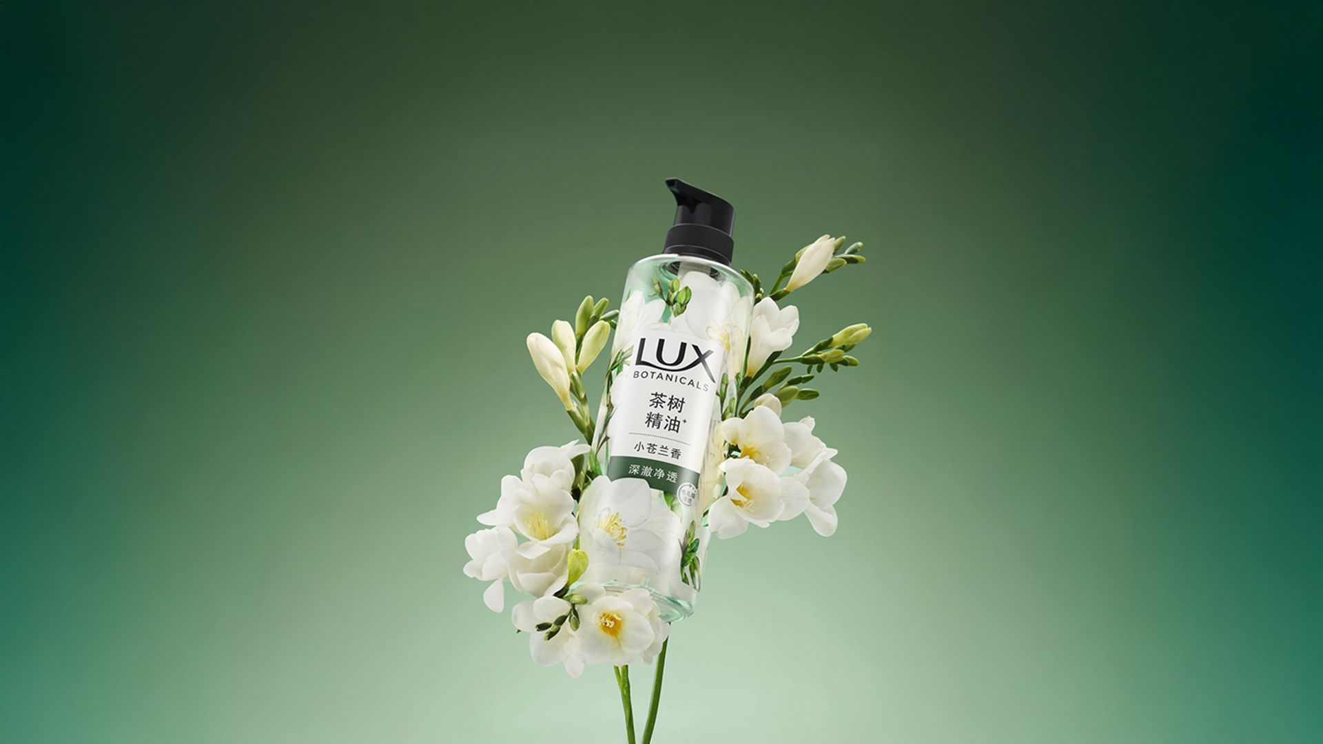A bottle of Lux Botanicals shower gel, placed on a stem of white flowers, with a green background.