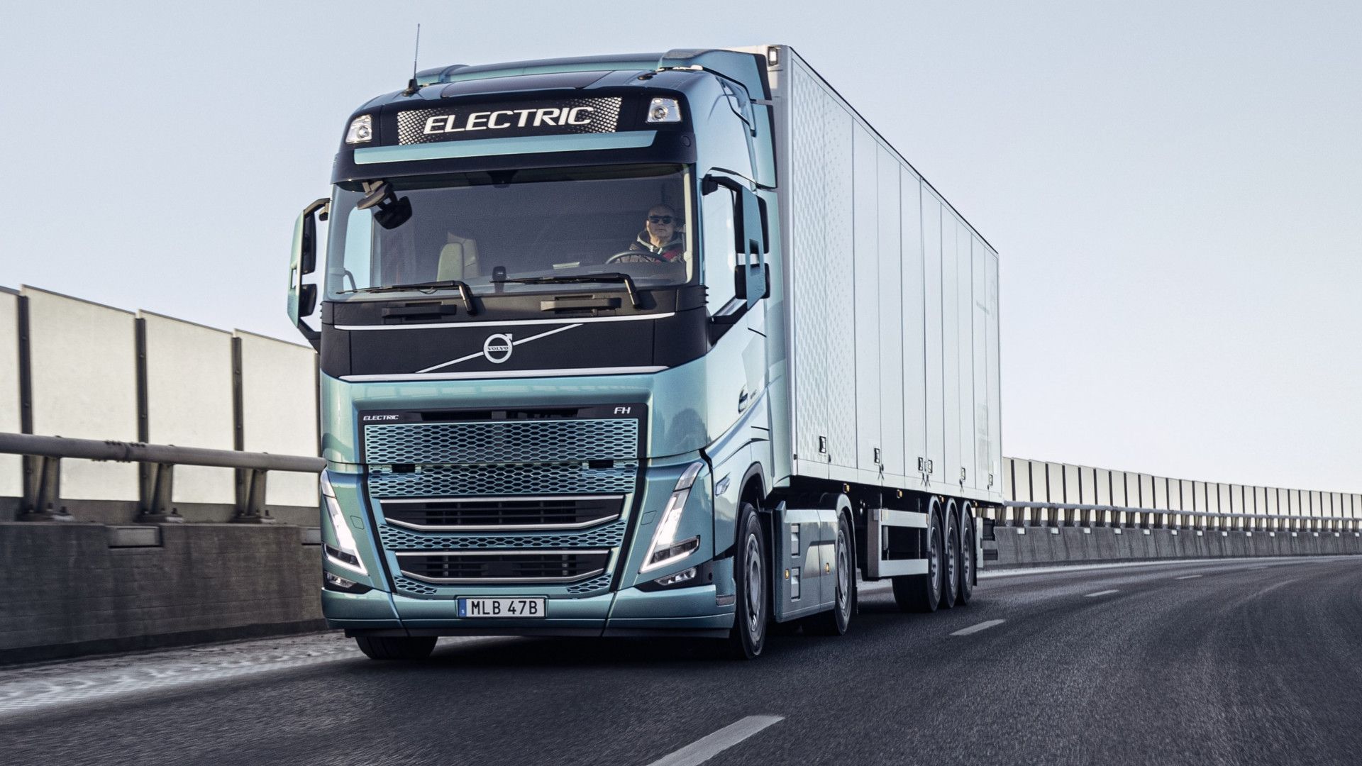 A green electric truck – one of the world’s first heavy-duty electric vehicles – being driven down a highway.