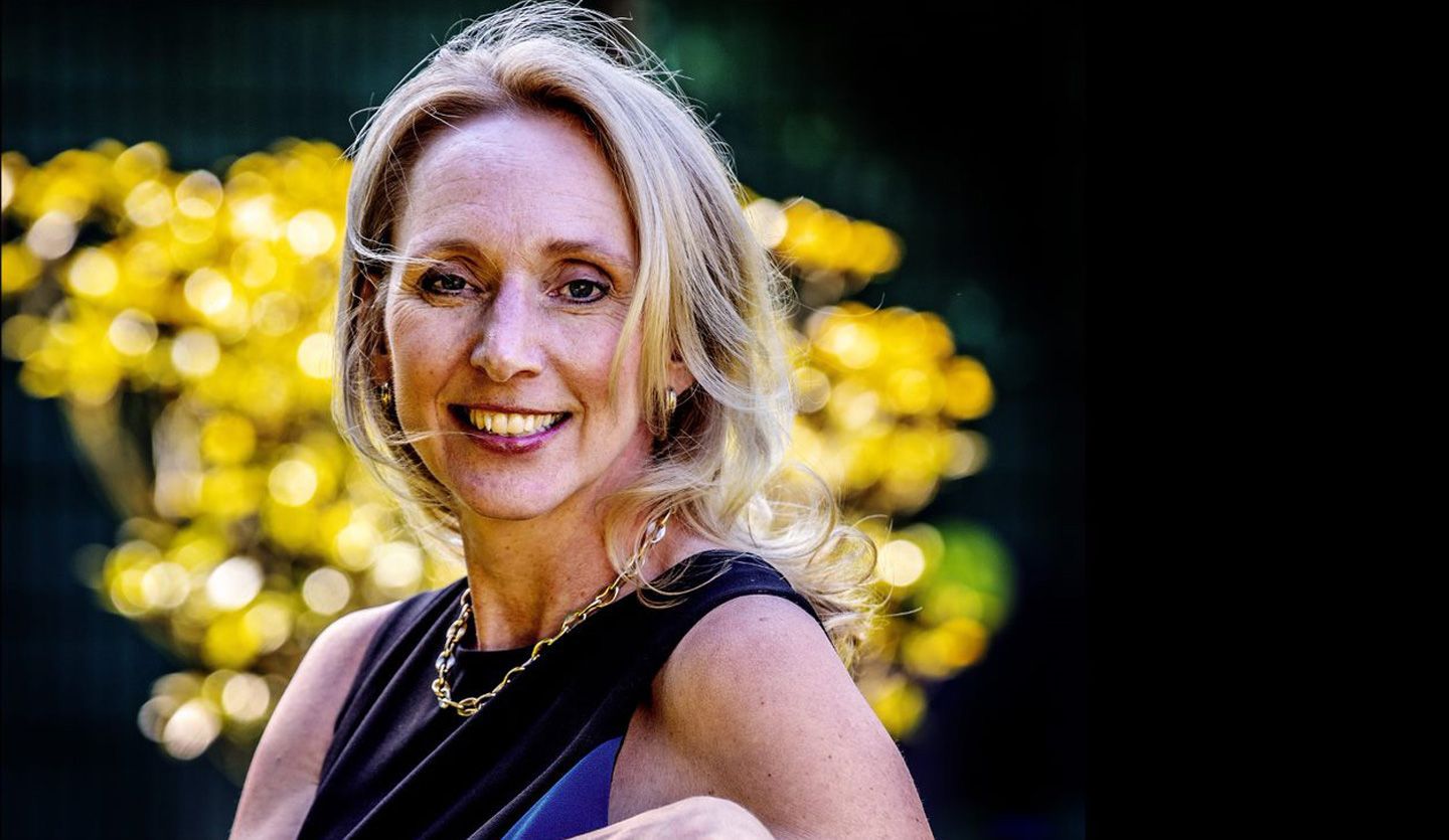 Hanneke Faber smiling in front of yellow flowers