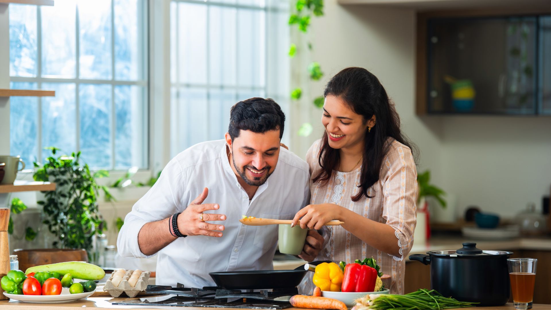 Couple cooking together in a kitchen with fresh vegetables.