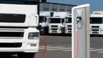 An electric truck recharges, with a fleet of electric trucks in the background.