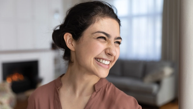 A woman wearing a light brown top smiling